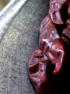 Photo of three dry red chillies on a brushed metal plate