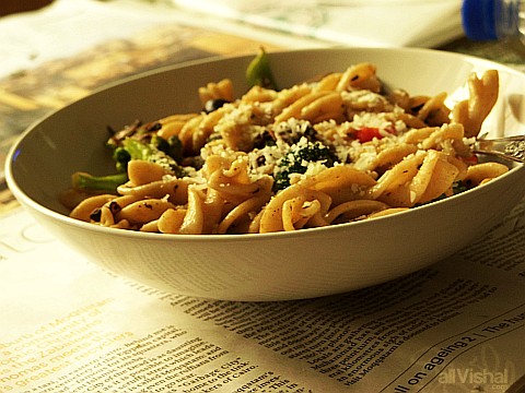 A bowl of broccoli and pepper fusilli on a newspaper
