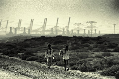 Two men walking with power plant in the bakground, Jebel Ali - after Two men walking with power plant in the bakground, Jebel Ali - after