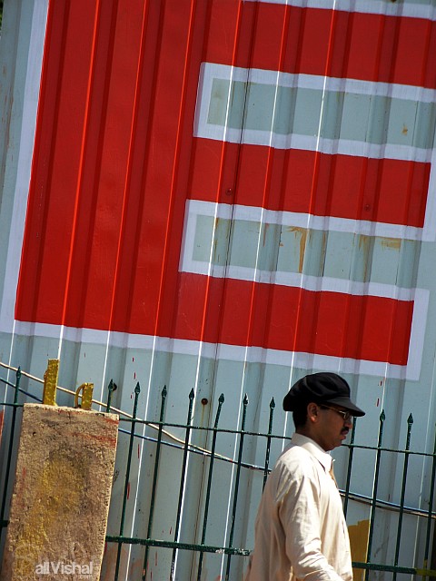 A man walks in front the letter E of a large roadside sign