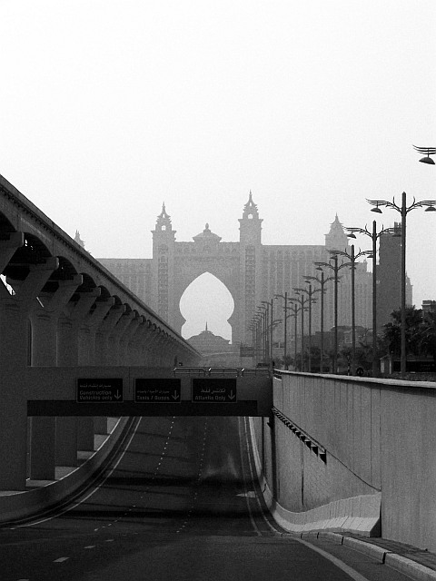A black and white photo of the road along the trunk of the Palm Jumeirah, with the Atlantis resort in the distance