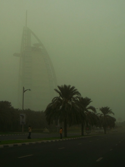 Couple taking a picture in front of the Burj Al Arab, obscured by the sandstorm